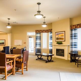 A cozy living room with a dining area, featuring a fireplace, comfortable chairs, and warm lighting.