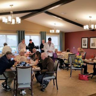 A group of seniors enjoying a meal together in a warm and inviting dining hall setting.