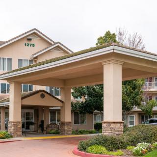 The entrance of a large building with a prominent canopy and landscaped surroundings.