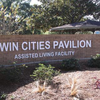 Sign for Twin Cities Pavilion Assisted Living Facility surrounded by landscaping.