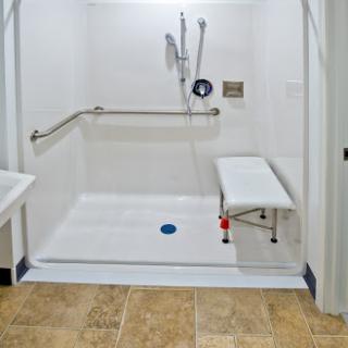 An accessible shower area designed for comfort and safety, featuring grab bars and a bench.