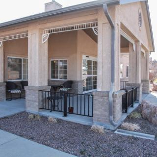 A residential building with a covered porch featuring outdoor seating and fenced area.