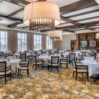 An elegant dining room with multiple tables and large chandeliers.
