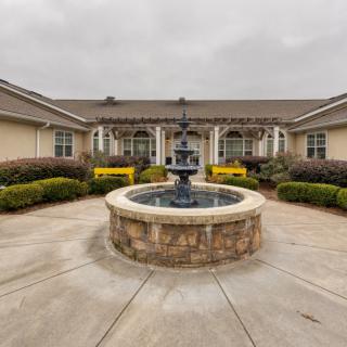 A courtyard featuring a central fountain surrounded by landscaping and a building.
