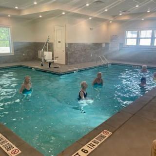 A group of people doing water aerobics in an indoor pool.