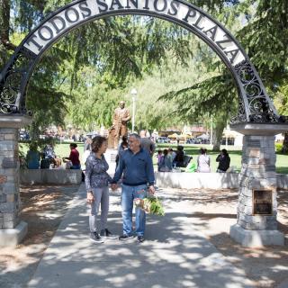 A couple holding hands under the archway at Todos Santos Plaza.