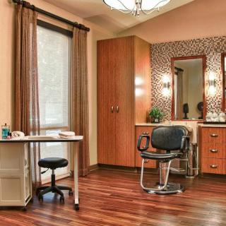 A well-organized hair salon interior featuring a styling chair, mirror, desk, and warm lighting.