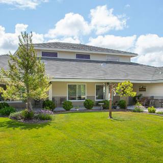 A suburban house with a well-maintained lawn and landscaping under a partly cloudy sky.