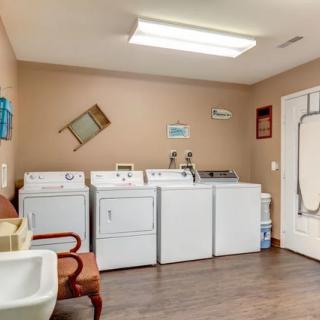 A well-organized laundry room with washers, dryers, and a sink.