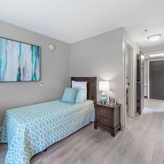 A modern bedroom with a single bed, blue bedding, and minimalist decor.