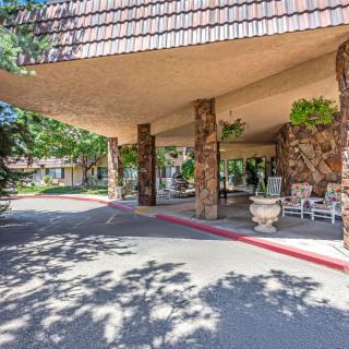 A covered entrance with stone columns and outdoor seating, surrounded by landscaping.