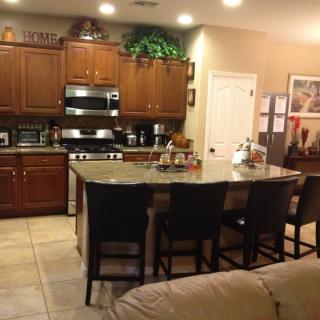 A modern kitchen with a central island and seating, featuring wooden cabinetry and stainless steel appliances.