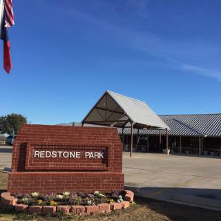 A view of the Peabody Park entrance, showcasing a welcoming sign against a clear blue sky.