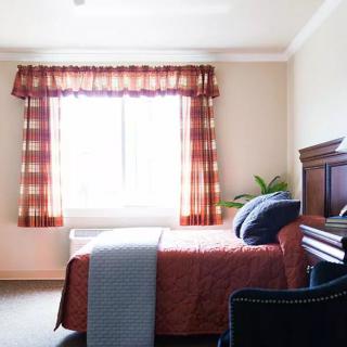 A cozy bedroom with a bed next to a window adorned with checkered curtains.
