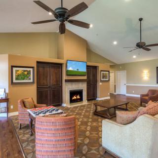 A cozy living room featuring a fireplace, comfortable seating, and a ceiling fan.