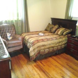 A cozy bedroom with a bed, armchair, and wooden furniture.