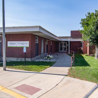 A view of a brick building with a welcoming entrance and well-maintained landscaping.
