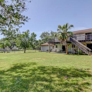 A spacious backyard with a large lawn, deck, and surrounding trees on a sunny day.