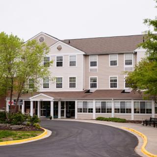 Front view of a hotel building with a driveway and trees.