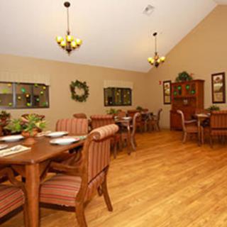 A warmly decorated dining area with wooden tables and chairs, complemented by soft lighting and wall decorations.