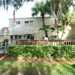 A charming residential building surrounded by lush greenery and palm trees.