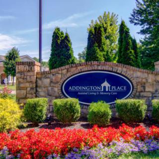 A welcoming entrance sign surrounded by colorful flowers and stone landscaping.