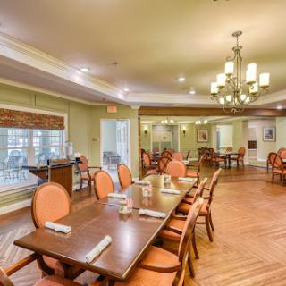 A cozy dining area featuring a wooden table surrounded by upholstered chairs, illuminated by a stylish chandelier.