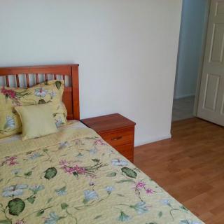 A neatly arranged bedroom with floral bedding and a wooden nightstand.