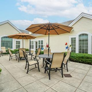 A well-maintained patio area with tables, chairs, and umbrellas outside a building.