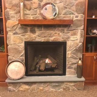 A cozy stone fireplace with decorative items on the mantel.