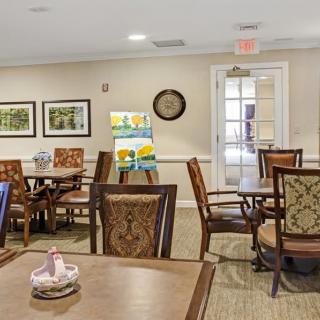 A cozy and well-decorated dining area with wooden tables and chairs, adorned with artwork and a wall clock.