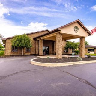 A well-maintained building with a covered entrance and surrounding landscaping on a sunny day.