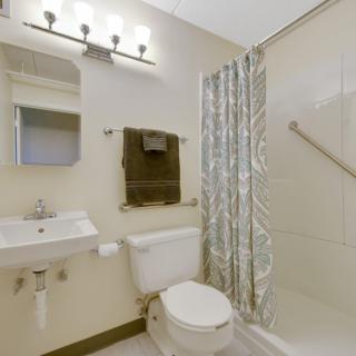 A clean and well-lit bathroom with a sink, toilet, and shower area.