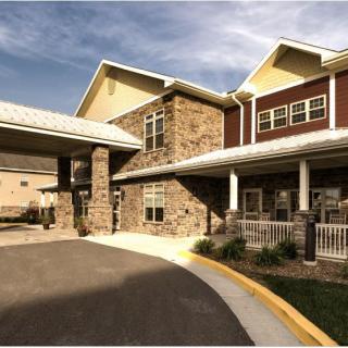 A modern residential building featuring a stone facade and covered driveway.