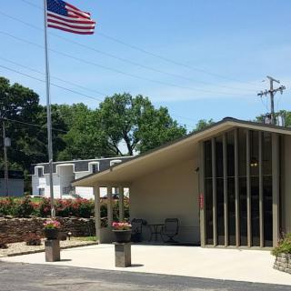 A small building with an American flag flying nearby on a sunny day.