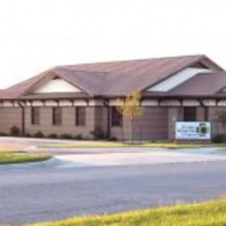 A small healthcare clinic building with a parking area in front.