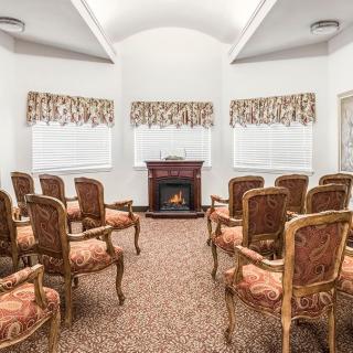 A small meeting room with ornate chairs and a fireplace.