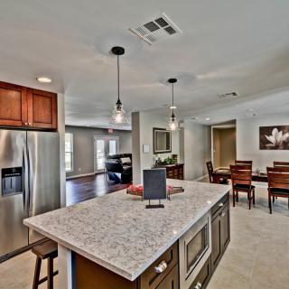 A modern open-concept kitchen featuring a large island with pendant lighting and stainless steel appliances, leading into a dining area.