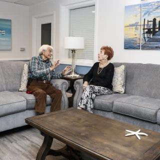 An elderly couple having a conversation in a cozy living room setting.