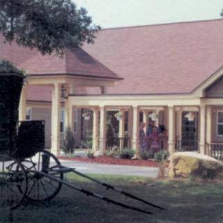 A horse-drawn carriage parked in front of a rustic building with a traditional design.