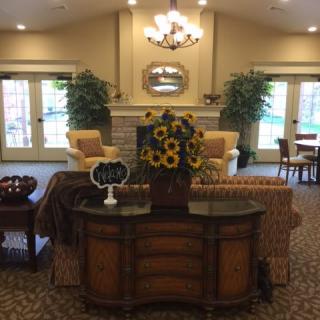A cozy living room with elegant decor, featuring comfortable seating, a chandelier, and vibrant plants.