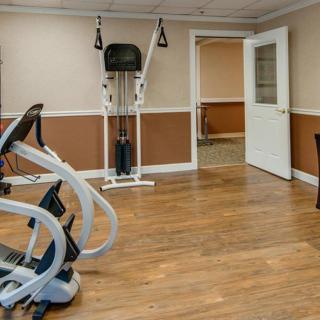 A small gym with exercise equipment and wooden flooring.