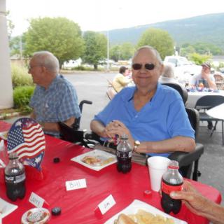 A group of people enjoying an outdoor gathering with food and drinks.