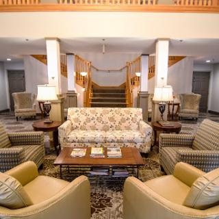 A cozy hotel lobby featuring a floral-patterned sofa, comfortable armchairs, and a welcoming atmosphere.