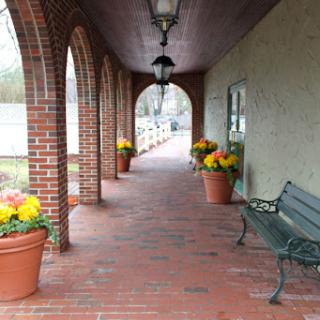 A serene corridor adorned with flower pots and elegant arches.