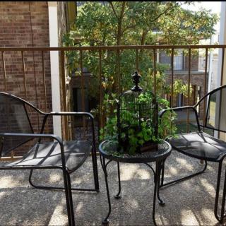 A cozy balcony with two chairs and a small table adorned with plants.