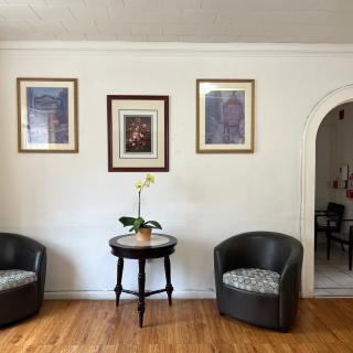 A cozy living room setup with two chairs, a small table with a plant, and framed artwork on the wall.