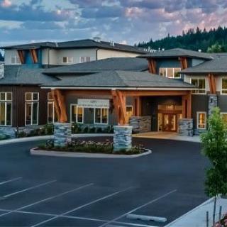 A modern commercial building with a welcoming entrance and adjacent parking lot during the evening.
