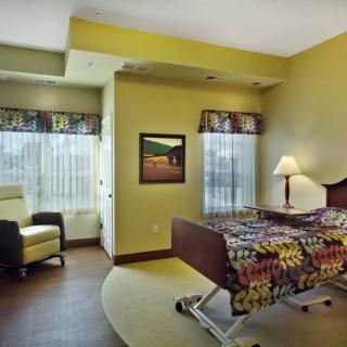 A well-lit hospital room with a bed and comfortable seating.