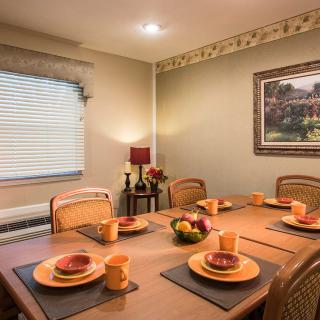 A warmly lit dining room with a neatly set table, complete with dinnerware and decorative elements.